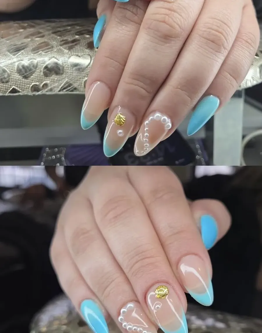 Uñas almendradas en celeste con perlas y una concha dorada