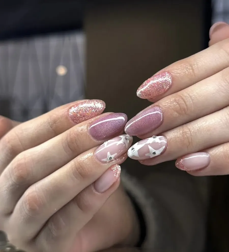 Uñas en rosado y lila con brillo y estrellas blancas